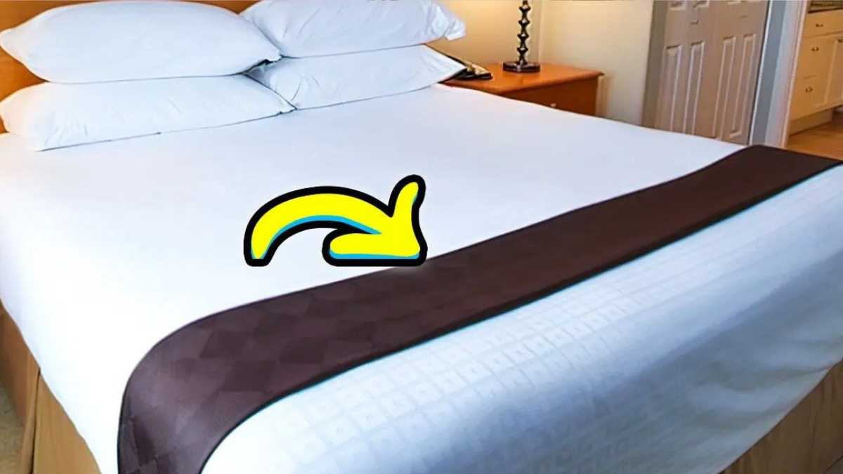 What is the purpose of the small blanket on the edge of the hotel bed?